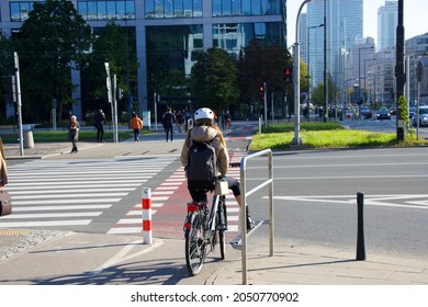 Cyclist At Zebra Crossing Wait For The Traffic Lights Change. Skyscrapers And A Modern City In The Background. Modern Eco Transport In The City. 