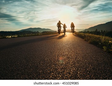 Cyclists family traveling on the road at sunset