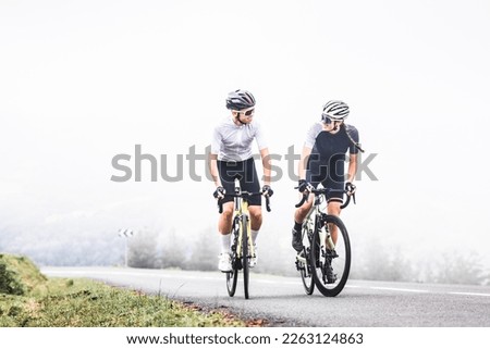 Cyclists man and woman couple riding together climbing a mountain at the Aiako Harriak natural park in the Basque Country.