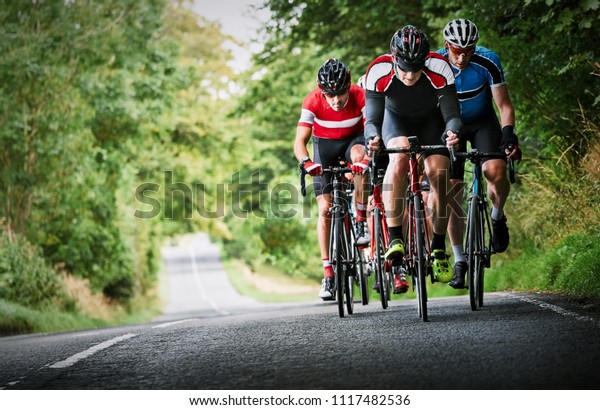 Cyclists racing on country roads on a sunny day in\
the UK.