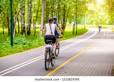 Cyclists Ride On The Bike Path In The City Park 