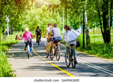 Cyclists Ride On The Bike Path In The City Park
