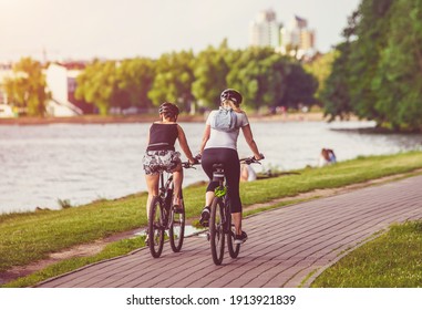 Cyclists Ride On The Bike Path In The City Park
