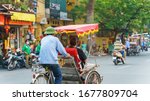 Cyclo driver taking tourist visiting old quarter on street in Hanoi