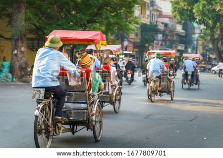 Cyclo driver taking tourist visiting old quarter on street in Hanoi
