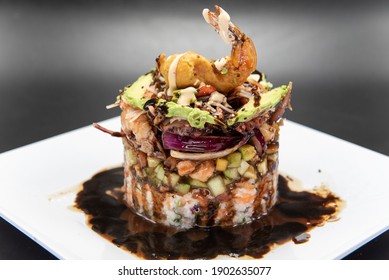 Cylidrical Tower Of Various Shellfish And Seafood Delicately Constructed Topped With Fried Shrimp.