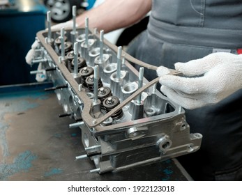 The cylinder head on the car mechanic's desktop. Close-up, side view. Check the condition of the spare part of the part before replacing it. Repair and maintenance of the car in the car service center