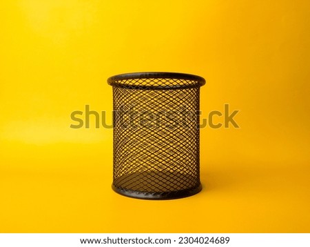 cylinder shaped metal net box pencil holder isolated on yellow background.