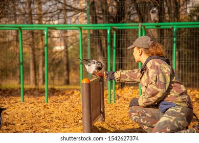 Cynologist On The Dog Playground Trains A Crow.Woman And Bird.