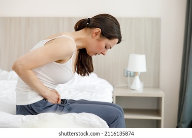 Cystitis In A Woman. A Young Woman Has A Pain In The Lower Abdomen, She Holds Her Stomach With Her Hand.