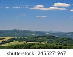 Czech Central Mountains landscape distant view meadows fields forest hills with TV tower blue sky and white clouds