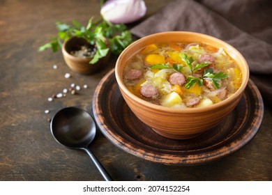 Czech food: Traditional Zelnacka cabbage soup with sausages and vegetables in a bowl on rustic wooden table. Copy space.