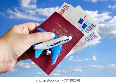 Czech passport - travelling by air - euro and Czech crown money with aircraft modell in the dand against blue sky