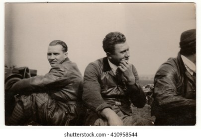 THE CZECHOSLOVAK SOCIALIST REPUBLIC - CIRCA 1950s: Vintage Photo Shows Men Wear Leather Jacket And Vest. They Have A Rest After Car Trip. Black & White Antique Photography.