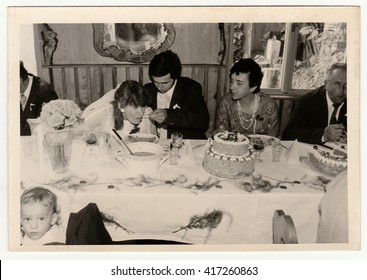 THE CZECHOSLOVAK SOCIALIST REPUBLIC - CIRCA 1970s: Retro Photo Shows People During Wedding Feast. Groom Feeds Bride. Black & White Vintage Photography.