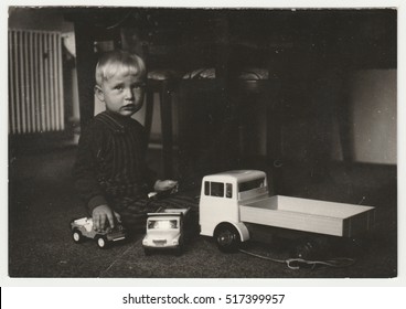 THE CZECHOSLOVAK SOCIALIST REPUBLIC - CIRCA 1970s: Vintage Photo Shows A Small Boy Plays With Toy Cars In The Living Room. Funny Photography Of A Cute Boy. Retro Black & White  Photography.