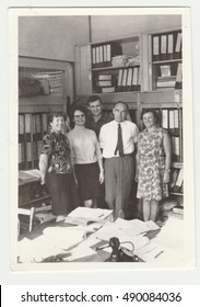 THE CZECHOSLOVAK SOCIALIST REPUBLIC - CIRCA 1980s: Vintage Photo Shows People (colleagues) Pose In The Retro Office. Retro Black & White  Photography.