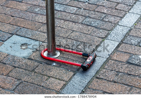 A D\
lock bike lock locked around a pole on the\
street