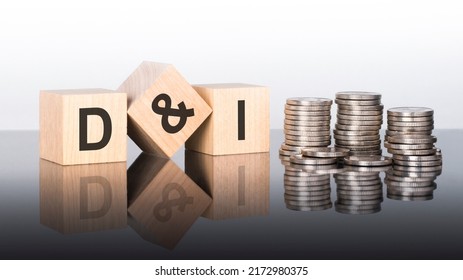 D and I - text is made up of letters on wooden cubes lying on a mirror surface, gray background. stacks with coins. inscription is reflected from the surface. d and i - short for Diversity Inclusion