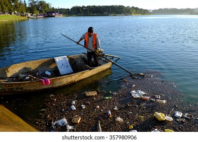 DA LAT, VIET NAM- DEC 30: Vietnamese Sanitation Worker Working On Boat To Fish Rubbish Out Of Water, Trash On Water Make Pollution, Scene Of Xuan Huong Lake At Dalat, Vietnam, Dec 30, 2015