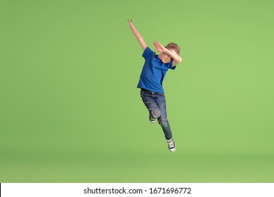 Dabbing. Happy Boy Playing And Having Fun On Green Studio Background. Caucasian Kid In Bright Cloth Looks Playful, Laughting, Smiling. Concept Of Education, Childhood, Emotions, Facial Expression.