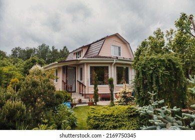 Dacha, a two-storey country house with large windows on the veranda, a stone porch and a green garden in the backyard. A cloudy summer day. Tver region, Russia