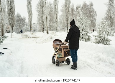 Dad With A Baby Carriage In Winter Walks In The Park