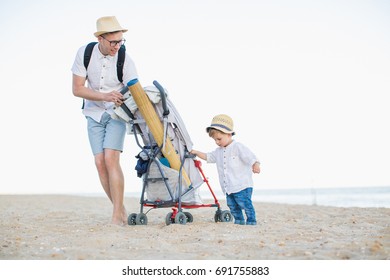 Dad With A Baby On The Beach With A Stroller