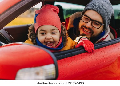 Dad And Baby Are Sitting In A Red Car In A Driver's Seat. Dad Tells The Child About The Device Of The Car. The Child Saw His Reflection In The Mirror Rear View And Is Very Happy. Time With Dad.