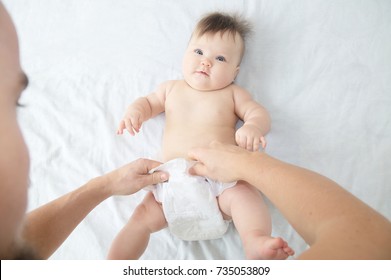 Dad Changing Diaper On Baby Girl On Bed, Changing Nappy, Everyday Care. Top View.