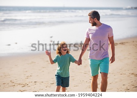 Dad and child having fun outdoors. Father and son walking on sea. Childhood and parenting concept.