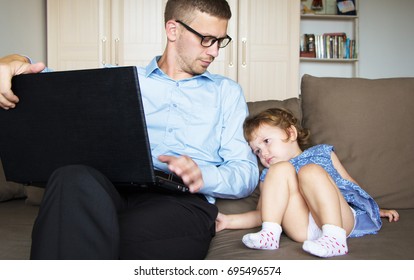 Dad With A Child Sitting At The Computer. Daughter Requires Father's Attention