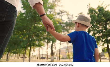 Dad, child, son are walking together in the park, holding hands. Dreams, happy family, childhood. Happy family walks down the street, kid, boy, father outdoors. Children's dreams, family values