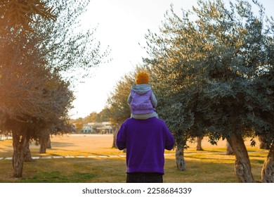 Dad and child are walking in the autumn park. Mediterranean climate. - Shutterstock ID 2258684339