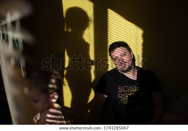 
dad with children plays at home on a sunny day.
family in the shade of the blinds. Dad and children having fun in
the bedroom on a sunny day. The shadow of the blinds in the room
with the family