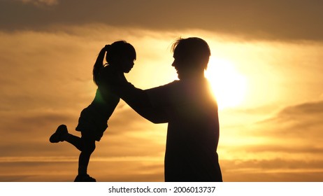 Dad Is Circling His Beloved Happy Daughter In His Arms. Silhouette Of Father And Child Playing Together At Sunset. Father And Little Child, Play In Park Outdoors In Sun. Family On Vacation. Childhood