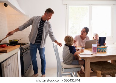 Dad Cooking Turns To Mum With Kids At The Kitchen Table