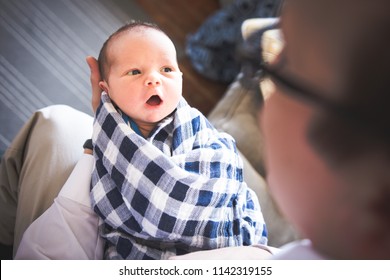 Dad Craddling Swaddled Newborn Baby In Arms