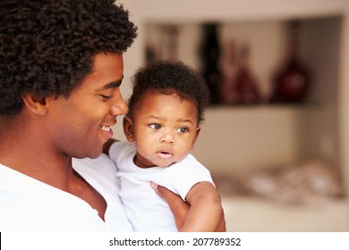 Dad Cuddling Baby Son At Home