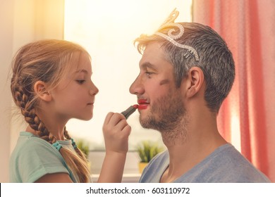 Papa mit süßer Tochter, die mit Lipstick für den Karneval behandelt wird