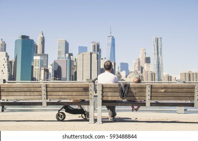 Dad And Daughter Enjoying Skyline Of New York Sitting On A Bench. Portrait About Family, Love And Travel