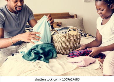 Dad and daughter folding clothes in bedroom together - Powered by Shutterstock