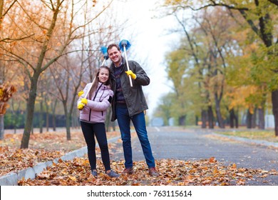 Dad With Daughter In Park With Brooms On Shoulders