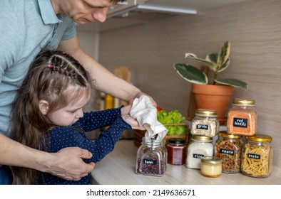 Dad and daughter pour cereal from a reusable bag into a glass jar. Storage in the kitchen. Zero waste. Conscious consumption. Lifestyle family. - Powered by Shutterstock