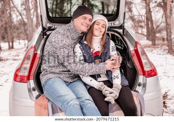 dad and daughter together. Dad and\
daughter at a picnic in winter. Two people are sitting in the trunk\
and talking. Winter weekend in nature in the car\
