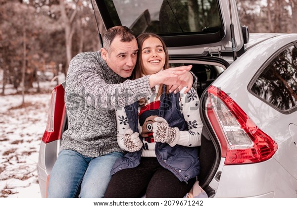 dad and daughter together. Dad and\
daughter at a picnic in winter. Two people are sitting in the trunk\
and talking. Winter weekend in nature in the car\
