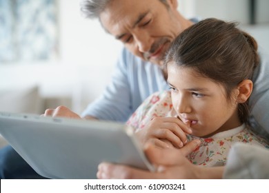 Dad with daughter websurfing on digital tablet