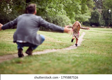 Dad Embracing Daughter After School In Park