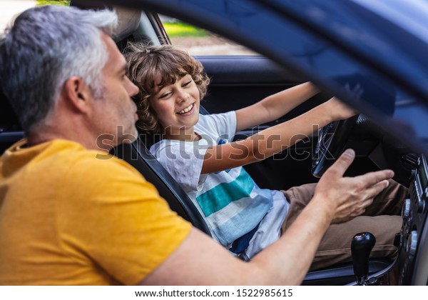 Dad explaining road rules to little son in the\
car. Driving lessons\
concept