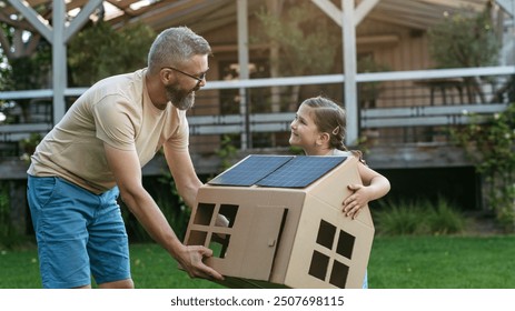 Dad and girl playing with house with solar panels on roof, learning about solar energy. Rooftop solar or photovoltaic system. Sustainable future for next generation. - Powered by Shutterstock